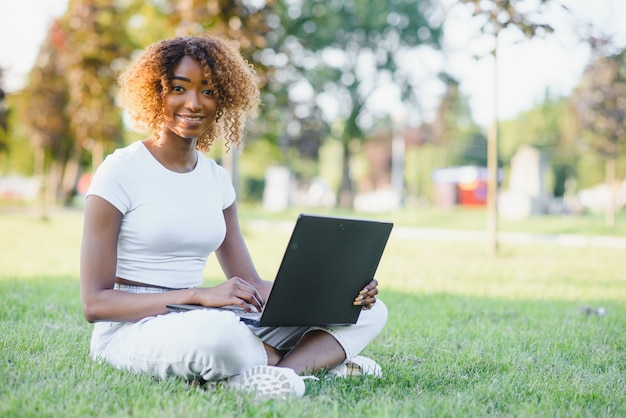 Jovem estudante universitária sentada no gramado