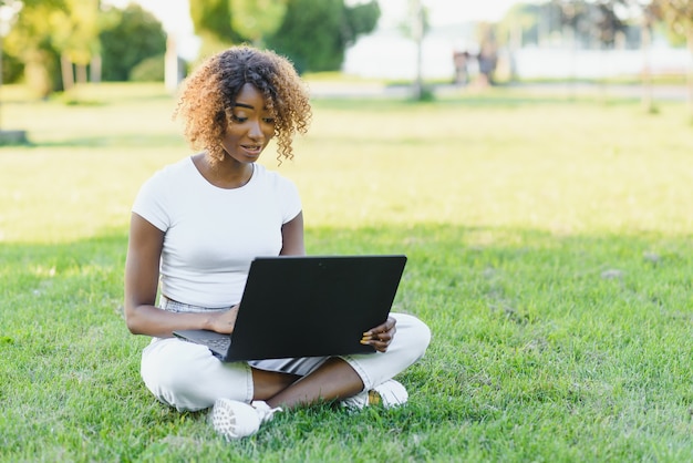 Jovem estudante universitária sentada no gramado