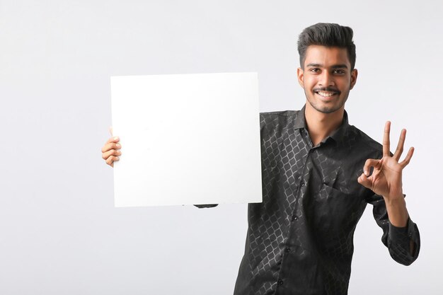 Jovem estudante universitário indiano mostrando a tabuleta em branco sobre fundo branco.