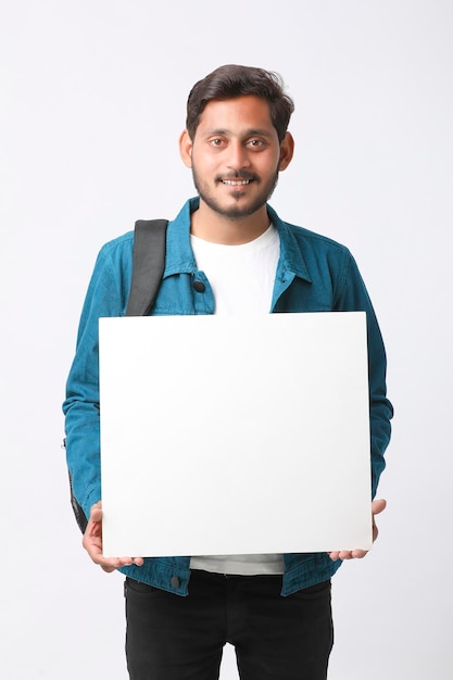 Jovem estudante universitário indiano mostrando placa de sinal em branco sobre fundo branco.