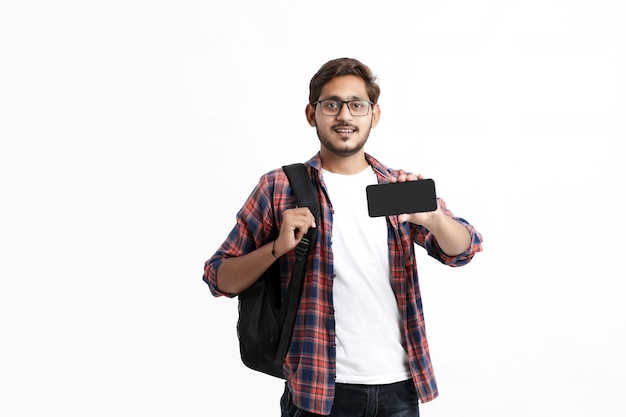 Jovem estudante universitário indiano mostrando tela do smartphone na parede branca