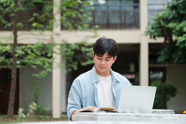 Jovem estudante universitário trabalhando em um laptop em uma escada no campus se preparando