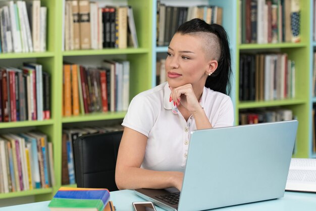 Jovem estudante usando seu laptop em uma biblioteca