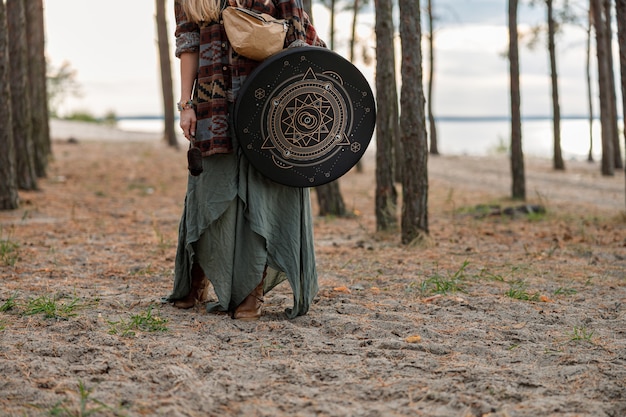 Foto jovem etnia xamã madura caminhando e tocando bateria, música meditativa