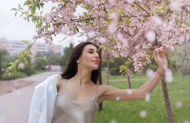 Jovem europeia com longos cabelos escuros em uma flor de sakura