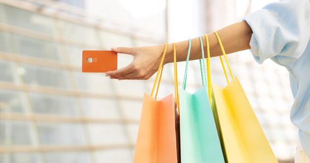 Jovem europeia viciada em compras com sacolas mostrando cartão de crédito na mão aproveita compras e tempo livre em