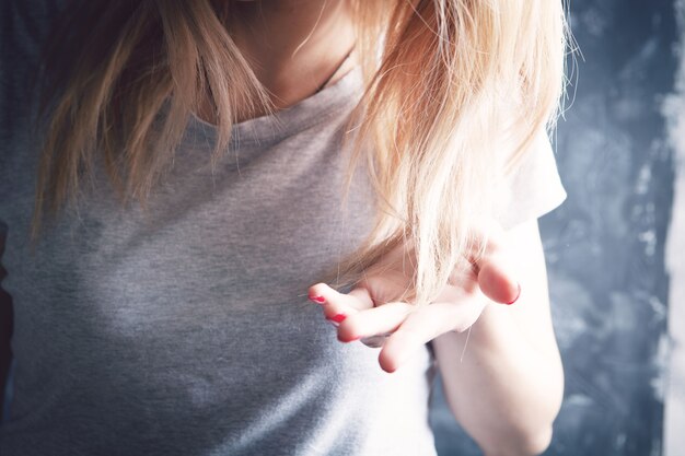 Jovem examina o cabelo dela. conceito de problema de cabelo em cinza