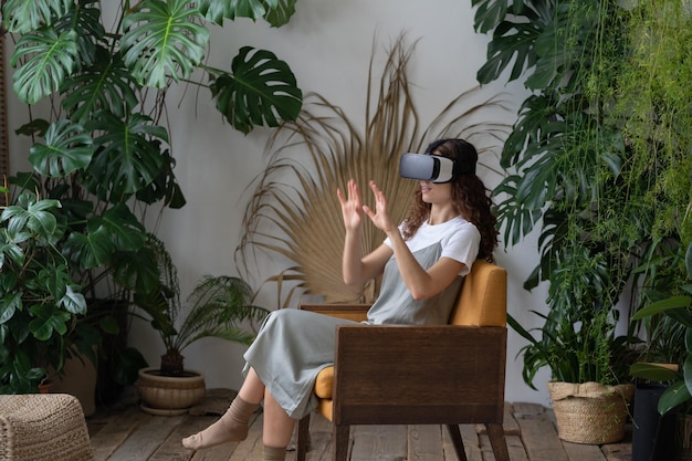 Foto jovem excitada usando óculos vr comprando ferramentas de jardim para jardinagem em casa em realidade virtual