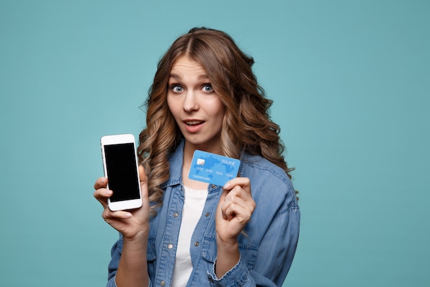 Jovem excitada usando telefone celular e segurando o crédito