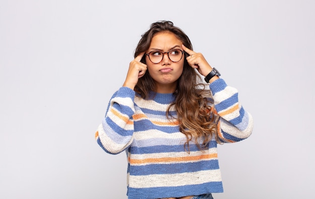 Foto jovem expressiva com óculos posando na parede branca