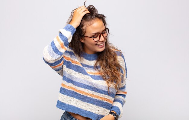 jovem expressiva com óculos posando na parede branca