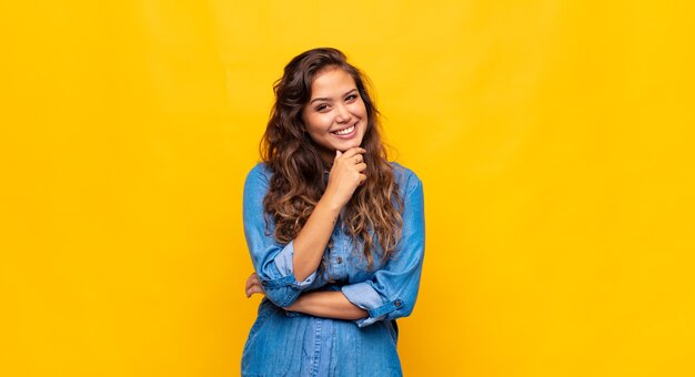 Jovem expressiva posando na parede amarela