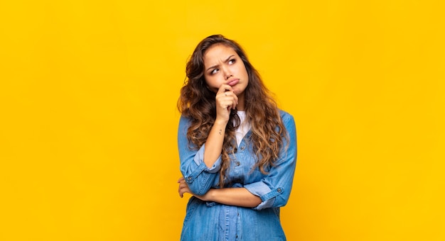 Jovem expressiva posando na parede amarela