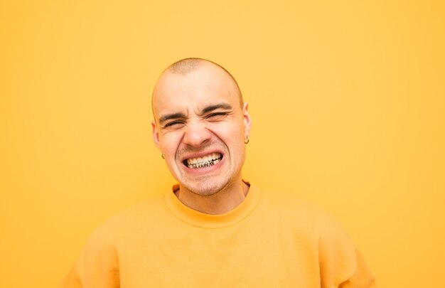 Foto jovem expressivo com um grillz nos dentes está zangado com um amarelo