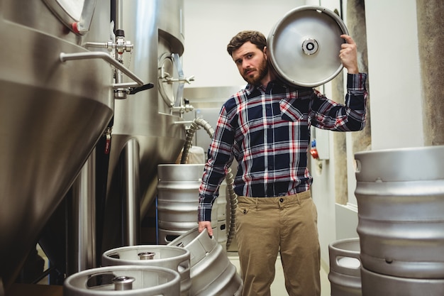 Jovem fabricante carregando barris em cervejaria