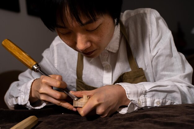 Foto jovem fabricante de violinos chinesa trabalhando com gouge para fazer um novo violino em sua oficina