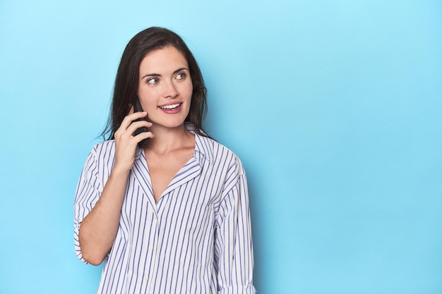 Jovem falando ao telefone contra o azul