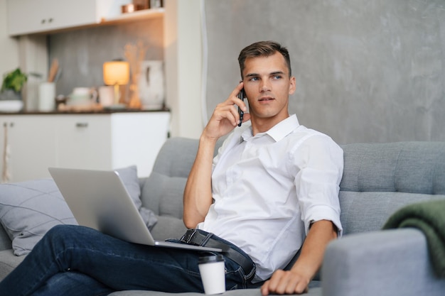 Jovem falando em um smartphone sentado no sofá