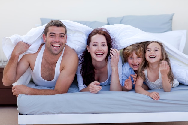 Foto jovem família brincando na cama juntos