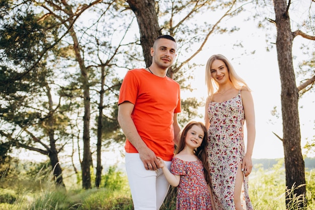 Jovem família feliz caminhando ao ar livre Os pais seguram a criança nas mãos e se alegram Eles estão felizes juntos Sorriam um para o outro