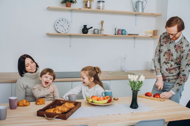 Jovem família feliz com dois filhos tomando café juntos.