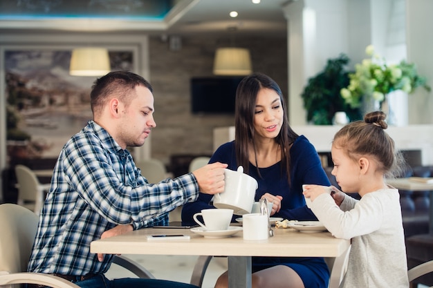 Jovem família feliz conversando em um restaurante