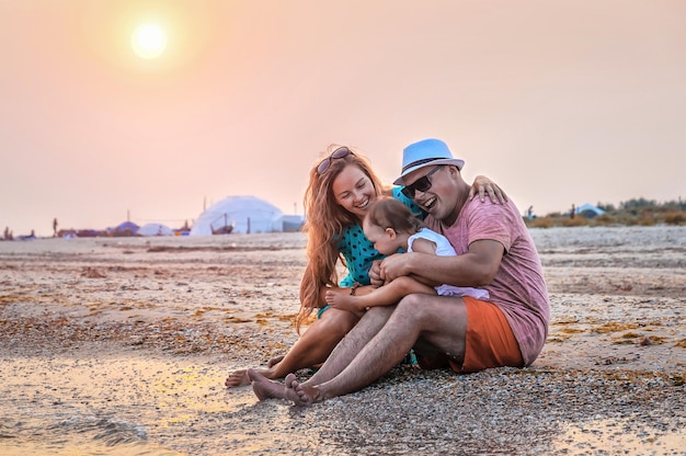 Jovem família feliz se diverte na praia do pôr do sol