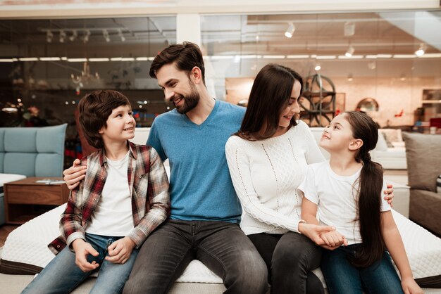 Jovem família feliz sentado no colchão abraçando