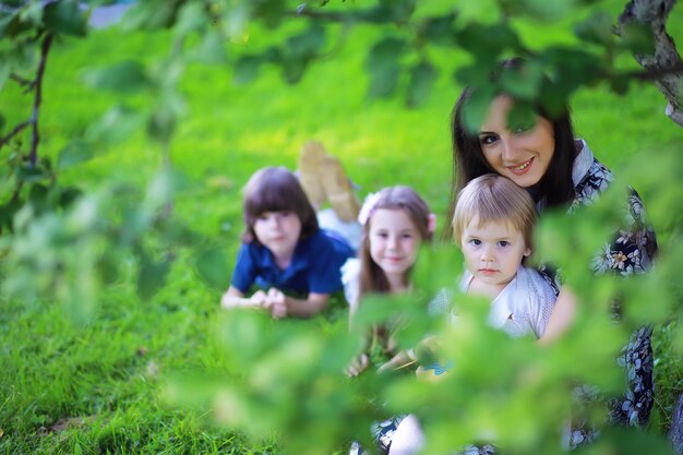 Jovem família grande em uma caminhada de manhã de verão. linda mãe com filhos está brincando no parque.