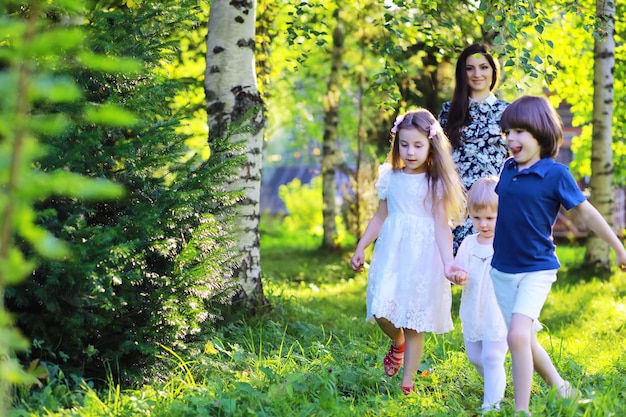 Jovem família grande em uma caminhada matinal de verão Linda mãe com filhos está brincando no parque