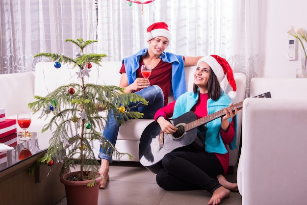 Jovem família indiana asiática comemorando o Natal com um presente usando chapéu de Papai Noel