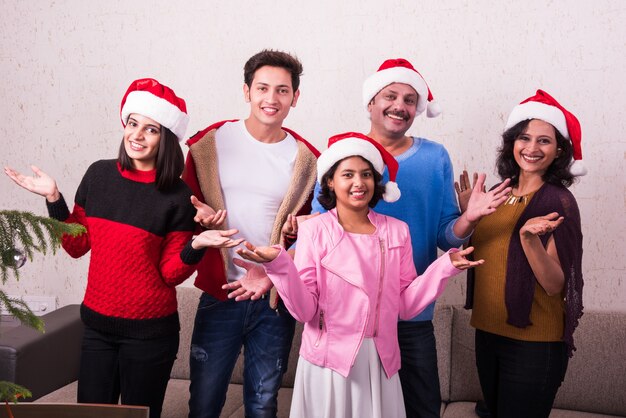 Jovem família indiana asiática comemorando o Natal com um presente usando chapéu de Papai Noel