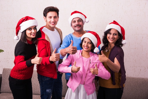 Jovem família indiana asiática comemorando o Natal com um presente usando chapéu de Papai Noel