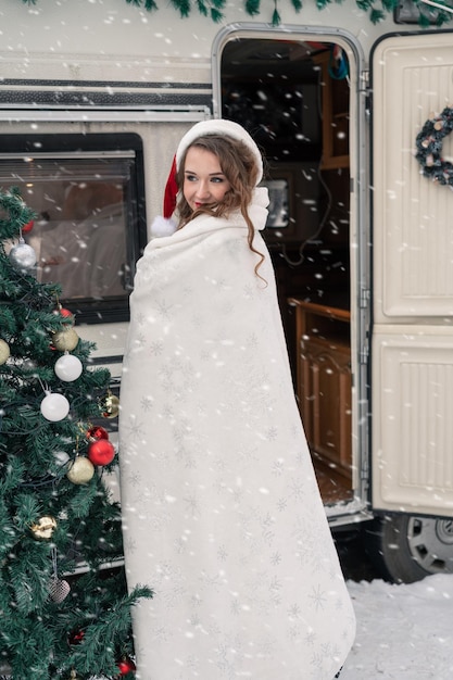 Foto jovem fantasiada de papai noel decora a árvore de natal no acampamento de inverno se preparando para o