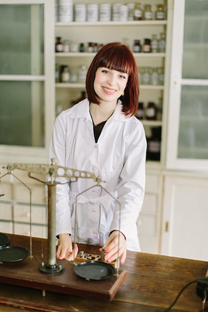 jovem farmacêutico lindo trabalhando com balanças antigas no laboratório de farmácia.