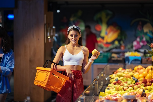 Foto jovem faz compras no supermercado escolhendo maçãs na loja