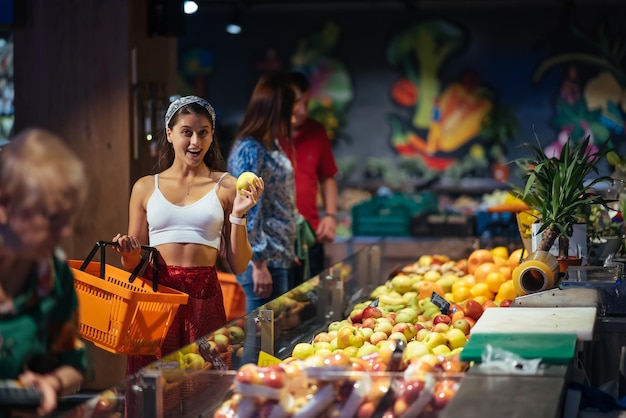 Foto jovem faz compras no supermercado escolhendo maçãs na loja