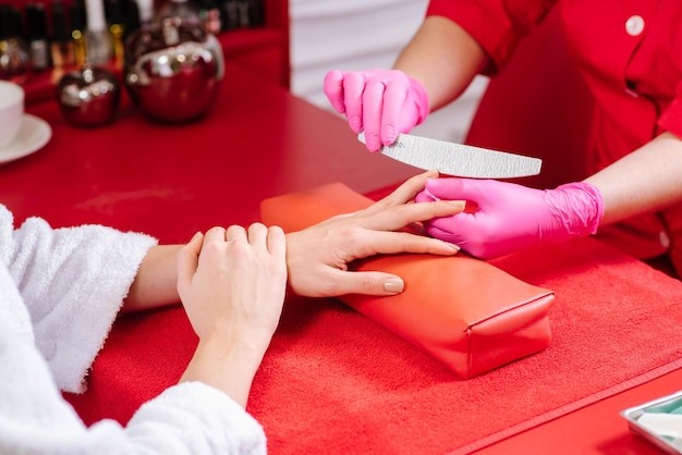 Jovem faz tratamento de manicure no salão de beleza