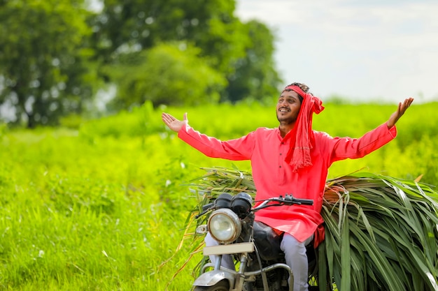 Jovem fazendeiro indiano com comida de gado em uma motocicleta