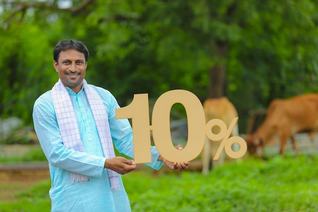 Jovem fazendeiro indiano mostrando dez por cento de tabuleiro em sua fazenda