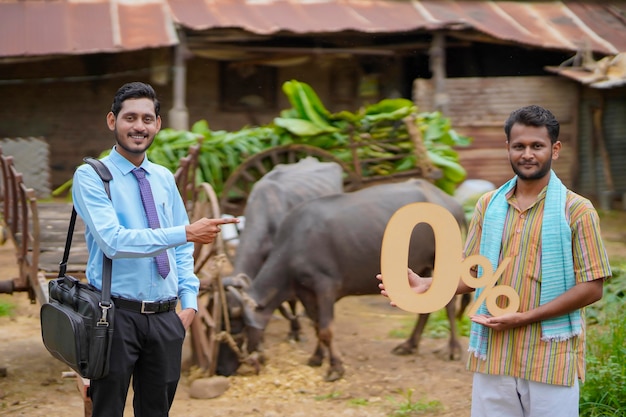 Jovem fazendeiro indiano mostrando o símbolo de zero por cento com agrônomo ou financista em sua fazenda de gado
