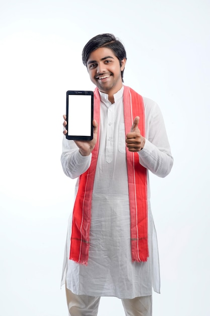 Jovem fazendeiro indiano mostrando smartphone ou tablet e dando expressão em fundo branco