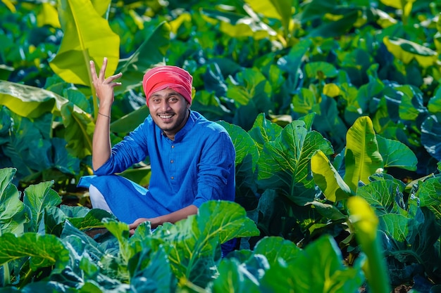 Jovem fazendeiro indiano olha para a terra, o campo de couve-flor