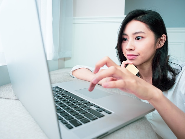 Jovem fazendo compras online com cartão de crédito e laptop em casa