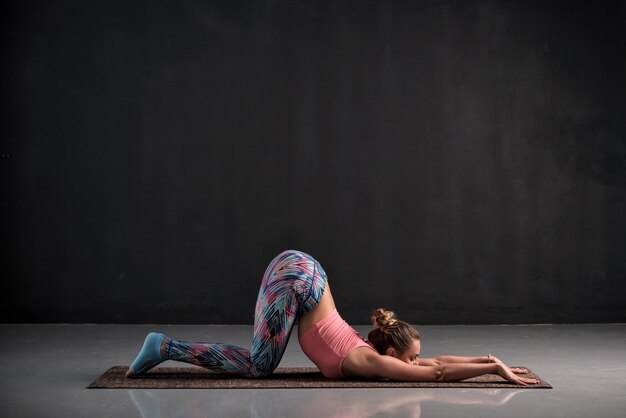 Jovem fazendo exercício de ioga Uttana shishosana ou pose estendida de cachorrinho