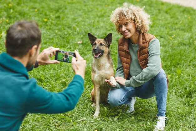 Foto jovem fazendo foto em seu celular de uma jovem e seu animal de estimação ao ar livre