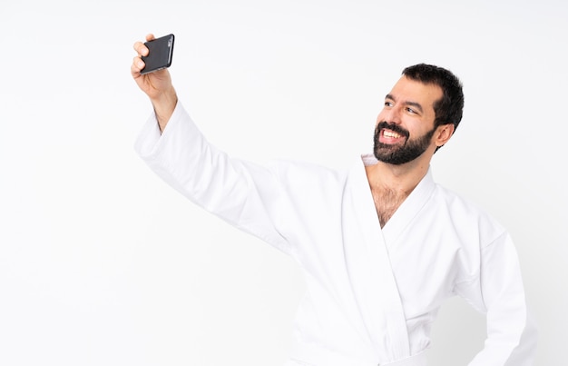 Jovem fazendo karatê sobre branco isolado, fazendo um selfie