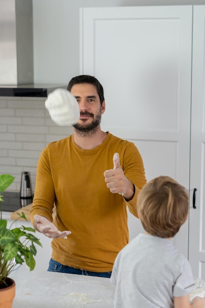jovem fazendo pão caseiro com seu filho na cozinha de sua casa