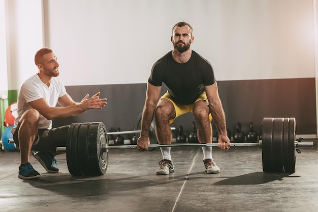 Jovem fazendo treino de crossfit com um personal trainer.