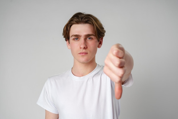 Jovem fazendo um gesto de polegar para baixo contra um fundo branco